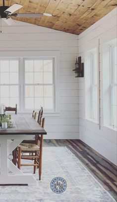 a dining table and chairs in a room with wood ceiling fans on either side of the windows