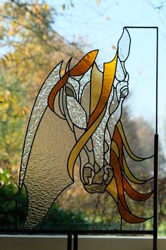 a stained glass window with an image of a horse on it's side and trees in the background