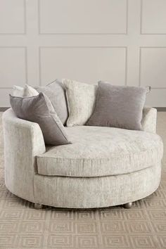 a round chair with pillows on it in front of a white paneled room wall