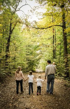 a family walking down a path in the woods holding hands and looking into the distance