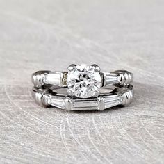 an engagement ring set with two baguettes on each band and a round diamond in the center