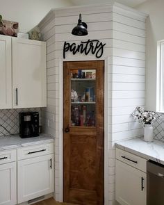 a kitchen with white cabinets and black lettering that says pantry on the wall above the door