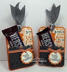 two halloween treat bags with candy bars tied to the top and ribbons on each bag