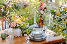 the table is set with plates, silverware and flowers in vases on it