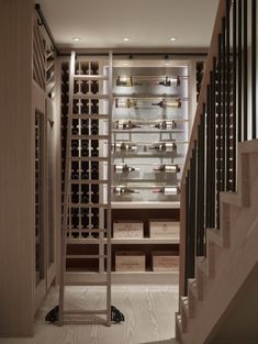 an empty wine cellar with stairs leading up to the second floor and bottles on shelves