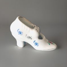 a white shoe with blue flowers painted on the bottom and sides, sitting on a gray surface