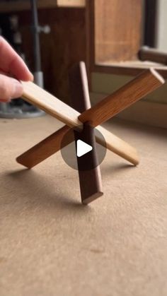 a person holding a piece of wood on top of a table