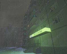 an apartment building lit up at night with snow on the ground and trees in the background