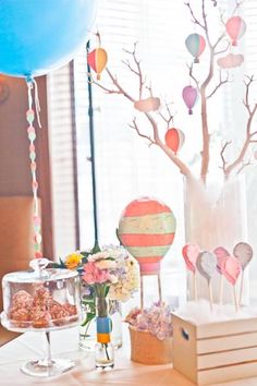 a table topped with candy and balloons next to a cake stand filled with candies