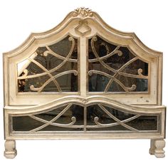 an ornate white wooden headboard with mirrored doors