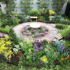 a circular garden with benches in the middle and lots of flowers on the ground around it