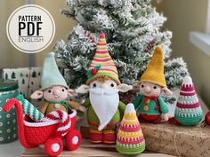 three crocheted gnomes sitting next to a christmas tree