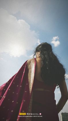 a woman in a red sari with her hands on her hips looking at the sky