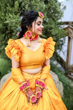 a woman in a yellow dress with flowers on her head and necklaces around her neck