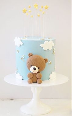 a blue and white cake with a brown teddy bear on it's top tier