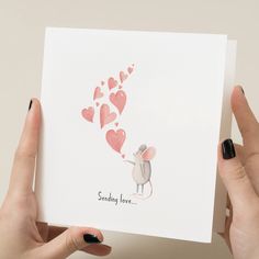 someone holding up a card with a mouse and hearts in the shape of a heart