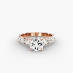 a rose gold engagement ring with three stones on the band and a round diamond in the center