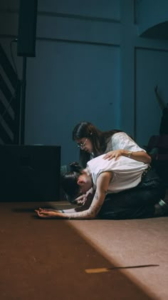 two people sitting on the ground in front of a laptop computer with their arms around each other