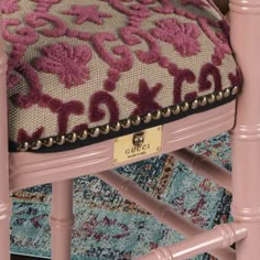 a close up of a pink chair with a decorative cushion on it's back