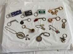 there are many different key chains on the white sheet that is laying on the bed