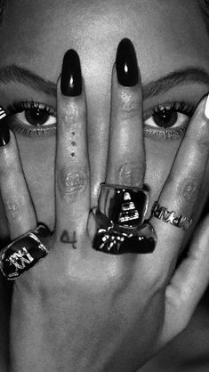 a woman with black and white nail polish holding her hands up to her face