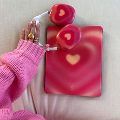 a woman's hand is holding two heart shaped earbuds