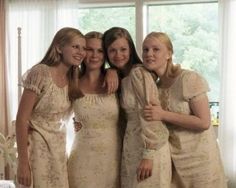 four women in white dresses standing next to each other with their arms around one another