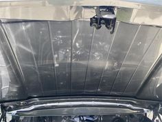 the engine compartment of a car with its hood up and it's hood covered in plastic