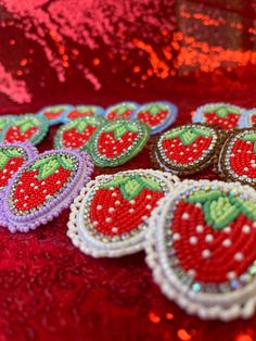 some very pretty red and green brooches on a shiny table cloth with sequins