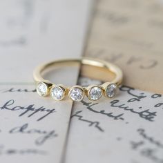 three diamond rings sitting on top of an old letter with writing in the back ground