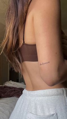 the back of a woman's stomach with a small tattoo on her left side