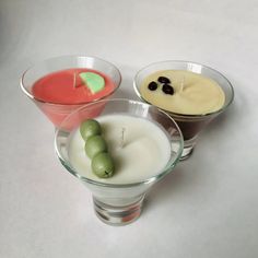 three glasses filled with different types of food on top of a white table next to each other