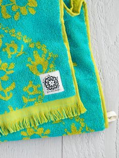 a green and yellow towel laying on top of a wooden floor next to a white wall