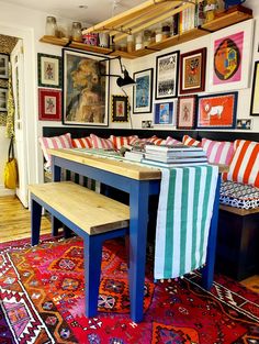 a dining room with colorful rugs and pictures on the wall behind the table, along with a bench