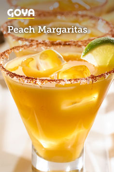 a close up of a drink in a glass on a table with the words goya peach margaritas