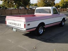 a pink and white truck parked in a parking lot