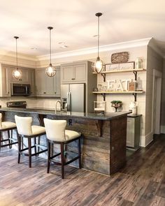 a kitchen with wooden floors and white stools next to an island in the middle