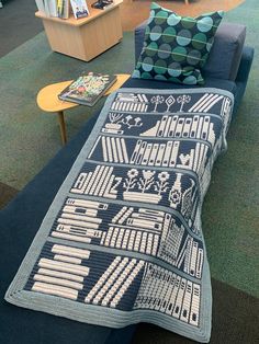 a couch with a blanket on top of it in a room filled with bookshelves