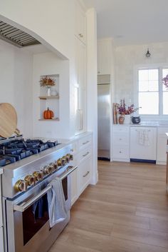 a kitchen with white cabinets and stainless steel stove top oven in the middle of it