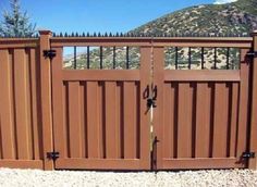 a brown fence with two gates in front of a mountainside area and blue sky