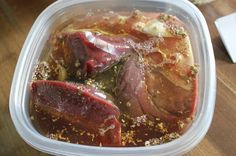 a plastic container filled with meat on top of a wooden table