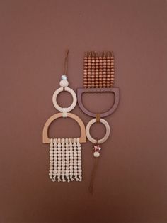 three pieces of wood and bead hanging on a brown wall, one is made out of beads