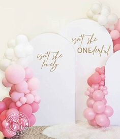 some balloons are in front of two white signs and one pink balloon is on the floor