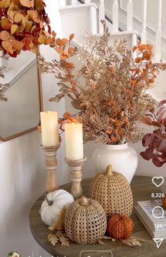 a table topped with candles and pumpkins next to a mirror