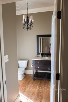 an open door leading to a bathroom with a chandelier hanging from the ceiling