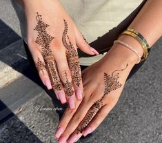 two hands with hendi tattoos on them, one is holding the other's hand