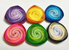 six skeins of multicolored thread on a white surface