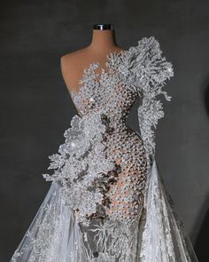 the back of a wedding dress with white flowers on it and sheer fabric overlays