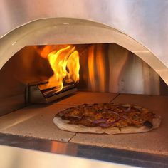 a pizza is being cooked in an oven with fire coming from the top and bottom