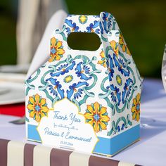 a white and blue box sitting on top of a table next to a plate with silverware